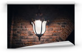 Big large forged vintage sconce lamp on a brick orange wall at night in the dark
