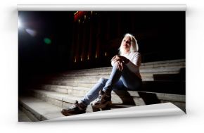 Ugly woman on the steps of stair in the city at night with lighting flashes in the black background