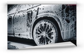 Commercial Photo of a Black Electric SUV Covered in Washing Soap and Foam. Close Up Shot of Foam Dripping from Car's Rear Fender onto the Family Car's Tyre and Rim