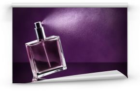 perfume bottle spraying on dark purple background