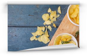Directly above shot of potato chips in bowl with rosemary on serving board at wooden table