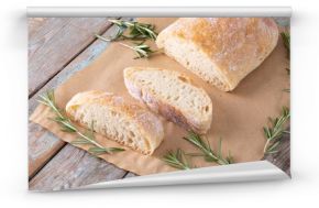 High angle view of bread with rosemary over brown wax paper at table