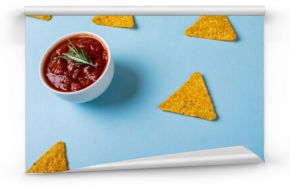 High angle view of red sauce with rosemary by nacho chips over blue background