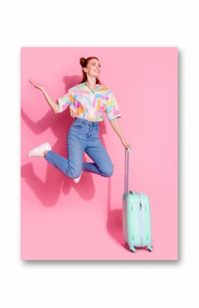 Full size photo of attractive girl colorful blouse jump hold suitcase palm hold offer look empty space isolated on pink color background