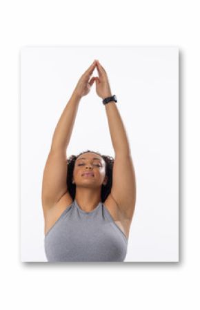 Biracial young female plus size model stretching arms above head, eyes closed, on white background