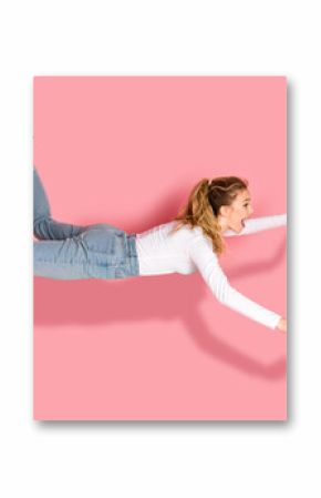 Young woman in casual attire appearing mid-air, striking a joyful and energetic pose against a vibrant pink background