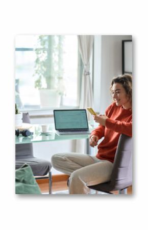 Young pretty woman holding smartphone using cellphone modern technology. Smiling lady looking at mobile phone while remote working or e learning from home sitting at table with laptop computer.