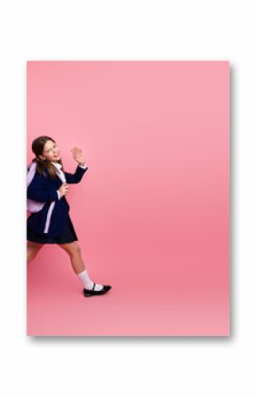 Happy student in formal school uniform on pink background, waving hand, education and back to school concepts