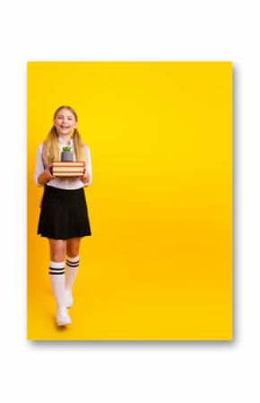 Cheerful schoolgirl standing against yellow background holding books and a small plant, representing education, joy, and learning