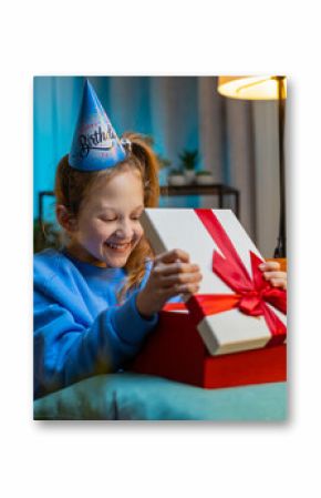 Happy preteen child girl wears festive birthday cap hat hold gift box with ribbon congratulating. Teenager Caucasian kid celebrating party event, opening delivery greeting present at home room on sofa