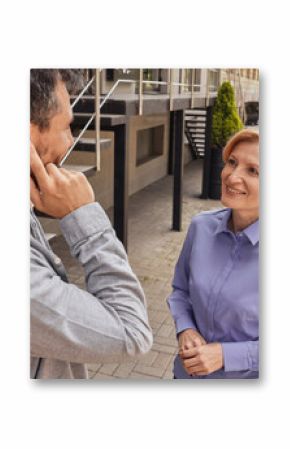 Two friends share a lively conversation outside in the urban environment, one using a hearing aid for clarity