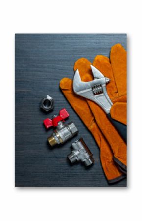 Adjustable wrench, ball valve with red handle, stainless steel tee fittings, leather safety gloves and rubber gaskets on wooden background, top view, copy space, closeup. Plumbing repair concept