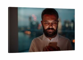 Businessman texting on smartphone, standing by window.
