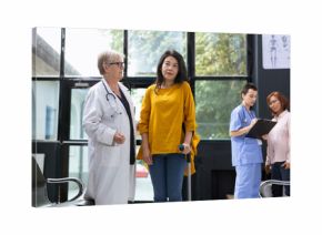 Doctor guiding patient with locomotor disability while using crutches for physical support in healthcare setting. Recovery journey includes walking exercises and professional advice.