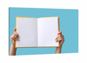 Hands of little girl holding open blank book on blue background