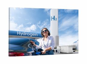 Woman holds a hydrogen fueling nozzle on a hydrogen filling station. Refueling car with hydrogen fuel