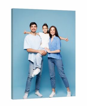 Full body young smiling fun happy parents mom dad with child kid girl wearing casual clothes hold daughter in hands look camera hugging isolated on plain blue background. Family day childhood concept.