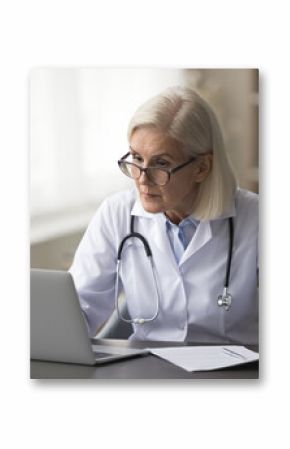 Mature woman therapist working on laptop, sit at desk with papers, prepare treatment plan, check patient medical records, make research and clinical guidelines, reviewing data, do administrative tasks
