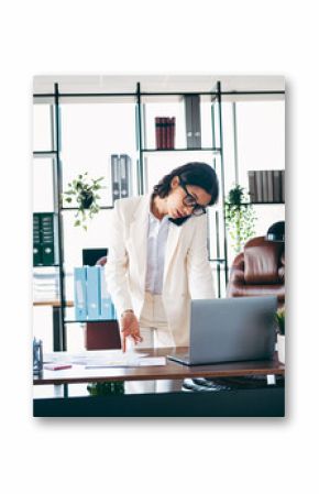 Confident female executive working in a modern office while multitasking with phone and laptop for professional productivity