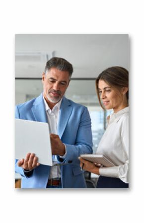 Busy professional smiling businessman and businesswoman leaders having conversation at work. Executives team of two business people working talking using laptop technology standing in corporate office