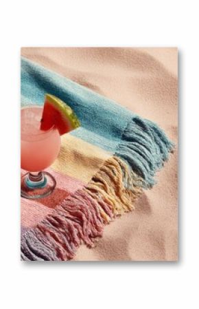 Beach towel and tropical drink on sand