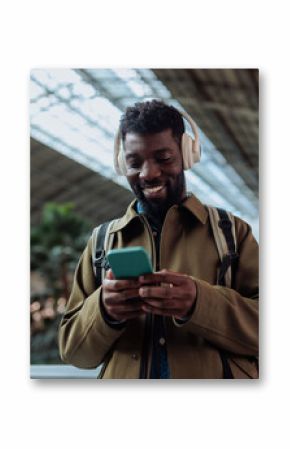 Tourist wearing headphones listening to music and browsing smart phone in airport