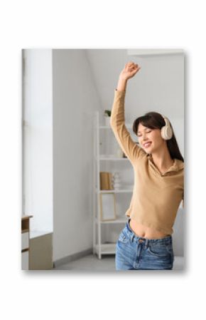 Smiling young woman in headphones dancing at home