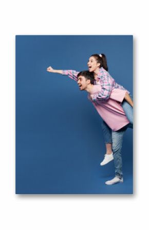 Full body young couple two friends family man woman wear pink casual clothes together give piggyback ride to joyful, sit on back run pov super hero isolated on plain blue background Lifestyle concept