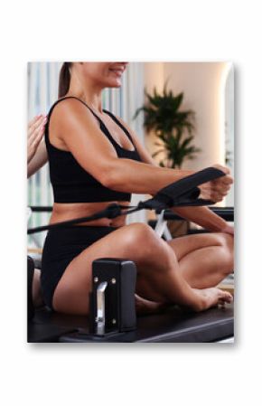 Woman exercising on reformer supervised by pilates instructor in studio, closeup