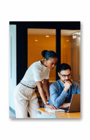 Two professionals analyzing data on a laptop in an office environment