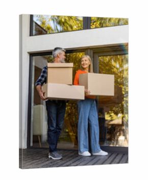 Senior couple carrying boxes together at home porch smiling