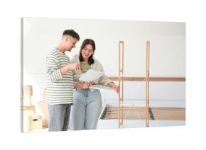 Young couple with instructions assembling shelving unit in bedroom on moving day