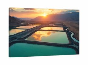 Aerial view of mineral mining evaporation ponds. Industrial landscape with brine pools reflects sunset light. Eco tech for lithium extraction in desert mountains. Critical raw material for electric
