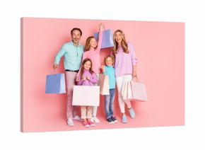 Happy family shopping day with parents and children posing with colorful bags against a pink background