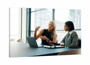 Two businesswomen discussing plans in a modern office setting