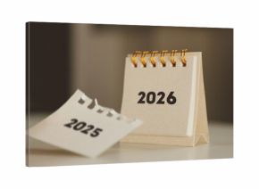 Turning the page from 2025 to 2026 – New Year calendar concept with hand and desk flip calendar 