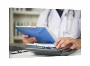 Close up of doctor hand using a calculator and holding a clipboard with medical paperwork. Concept of healthcare costs, medical insurance premiums, hospital fees, and financial administration.