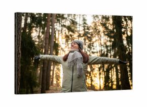 Woman in forest in winter. Happy in nature in Finland. Trees in woods. Healthy Finnish outdoor lifestyle. Smiling person arms raised. Fresh air.