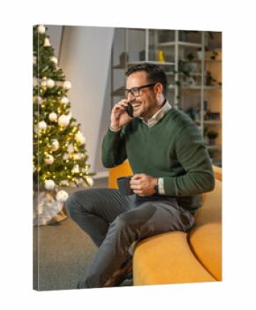 Man making phone call sitting by christmas tree in office