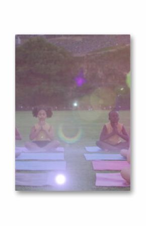 Image of lights over diverse pupils practicing yoga outdoors
