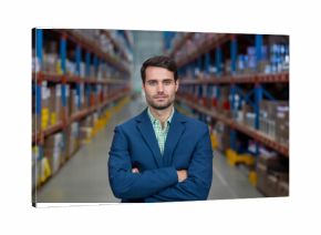 Male warehouse manager is standing in aisle lined with racks of inventory under fluorescent lights