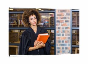 Orange hardcover book resting on wooden table under warm lights in library with glass partitions