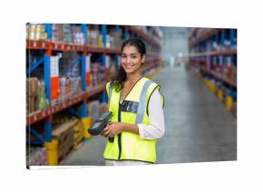 Asian female worker scanning boxes on pallets with scanner next to racks in warehouse under lights