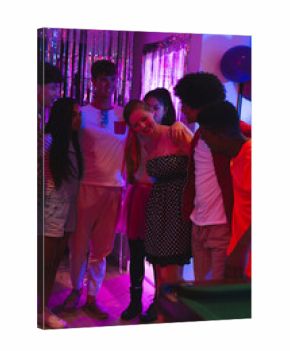 Teen friends celebrating together at home, enjoying party with colorful lights