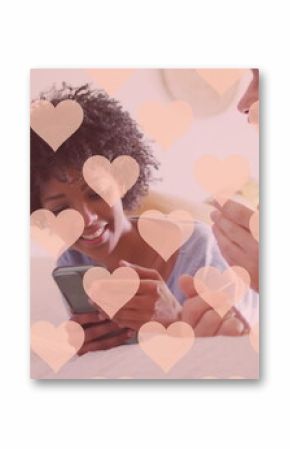 Image of hearts over happy diverse couple using smartphone