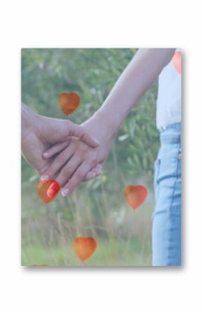 Image of red heart balloons floating over mid section of couple in love holding hands in summer