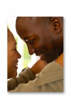 Smiling multiracial couple embracing closely, sharing intimate and loving moment together