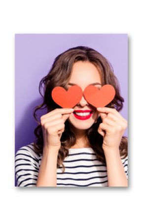 Portrait of lovely creative girl with white teeth red pomade covering closing eyes with two carton paper small little heart figures love signs isolated on violet background