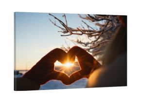 Heart shape symbol of the women mittens in winter frosty sunset. Concept of winter, dating, valentines day and love