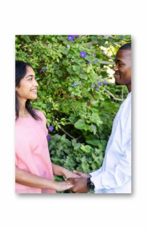 Couple holding hands and smiling, celebrating love in lush garden setting